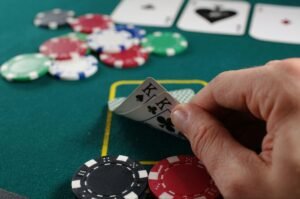 A hand holding two kings in a poker game, surrounded by colorful chips on a green table.