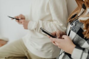 Two people holding smartphones, engrossed in screens.